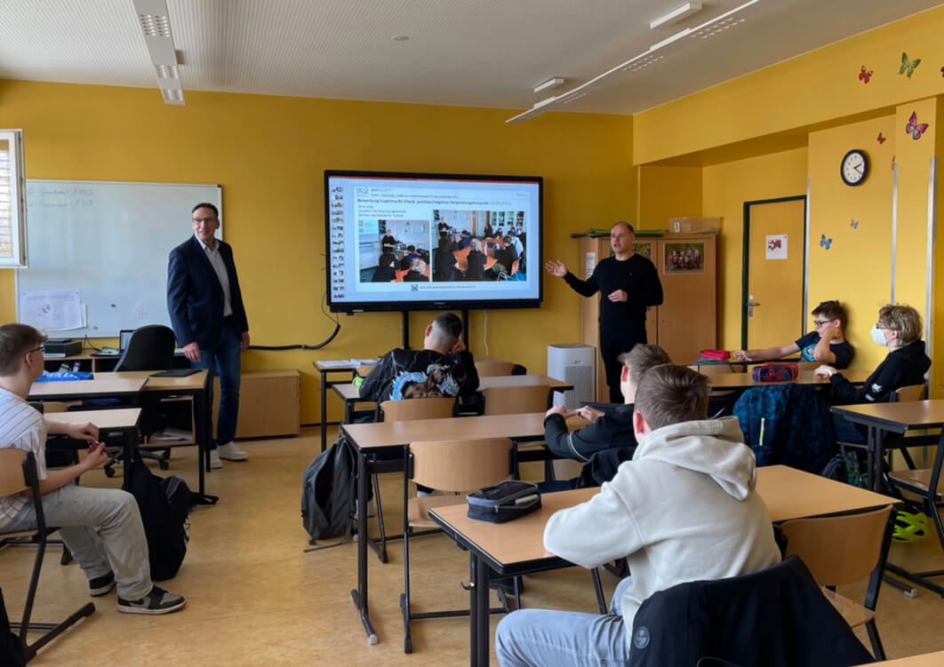 Bild: Janusz-Korczak-Schule, Projekt Bild Finaler Tag, Auswertung und Prämierung in Schule, Herr Schinck erklärt vor Smartboard